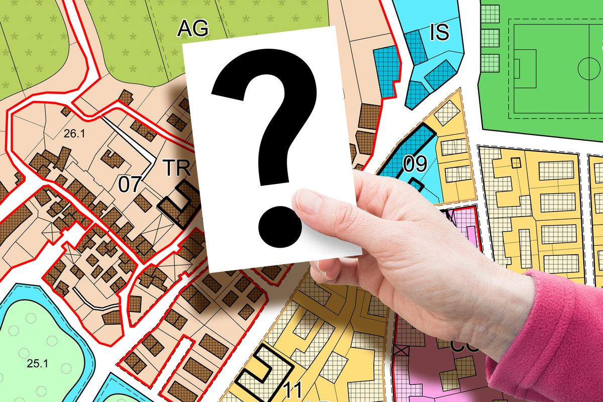 Hand holding a question mark card over a zoning map.